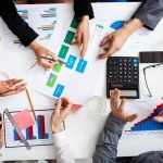 Picture of businessmen's hands on white table with documents, coffee and drafts